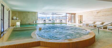 A spa area with a hot tub, lounge chairs, and a view of the mountains.