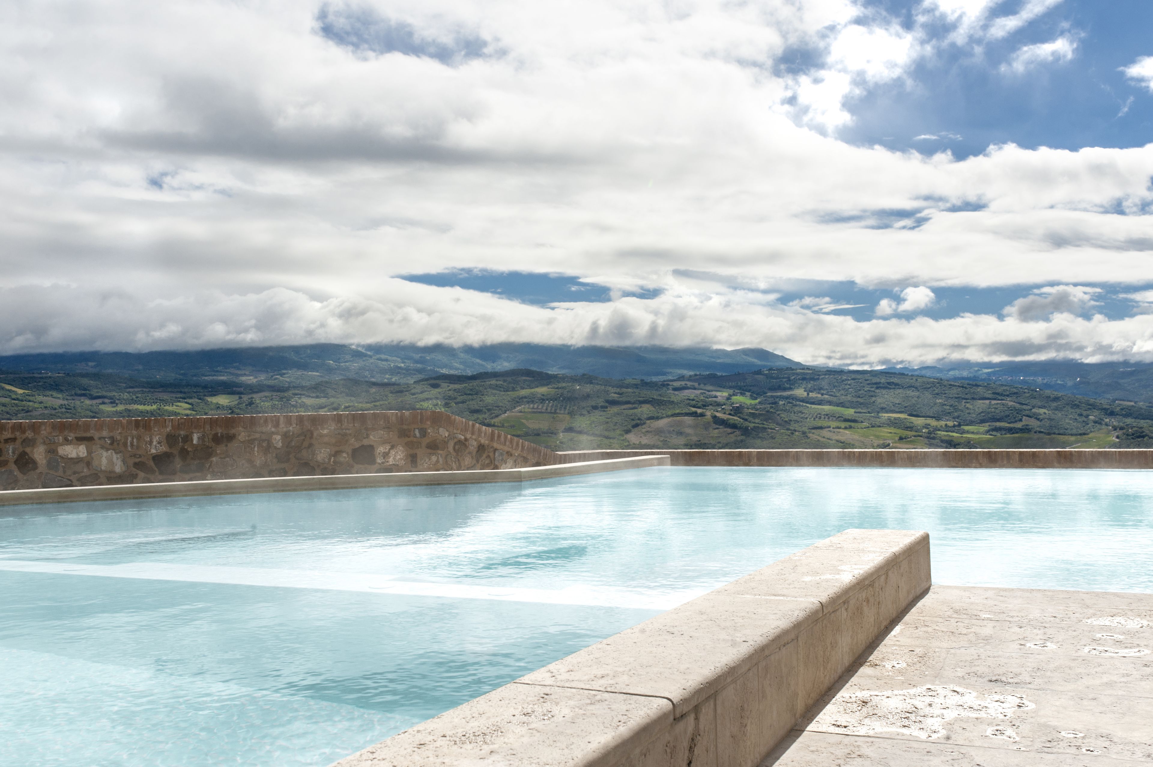 A swimming pool with a view of mountains and cloudy sky.