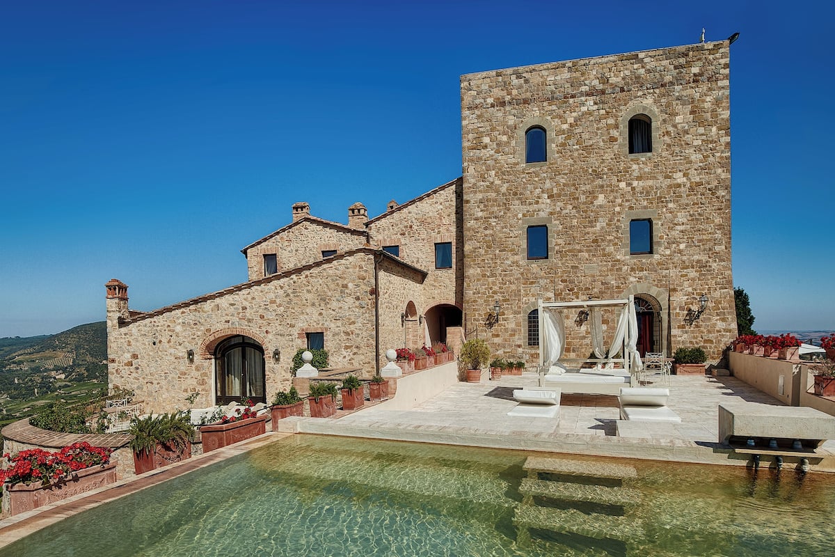 A stone building with a pool and outdoor seating area.