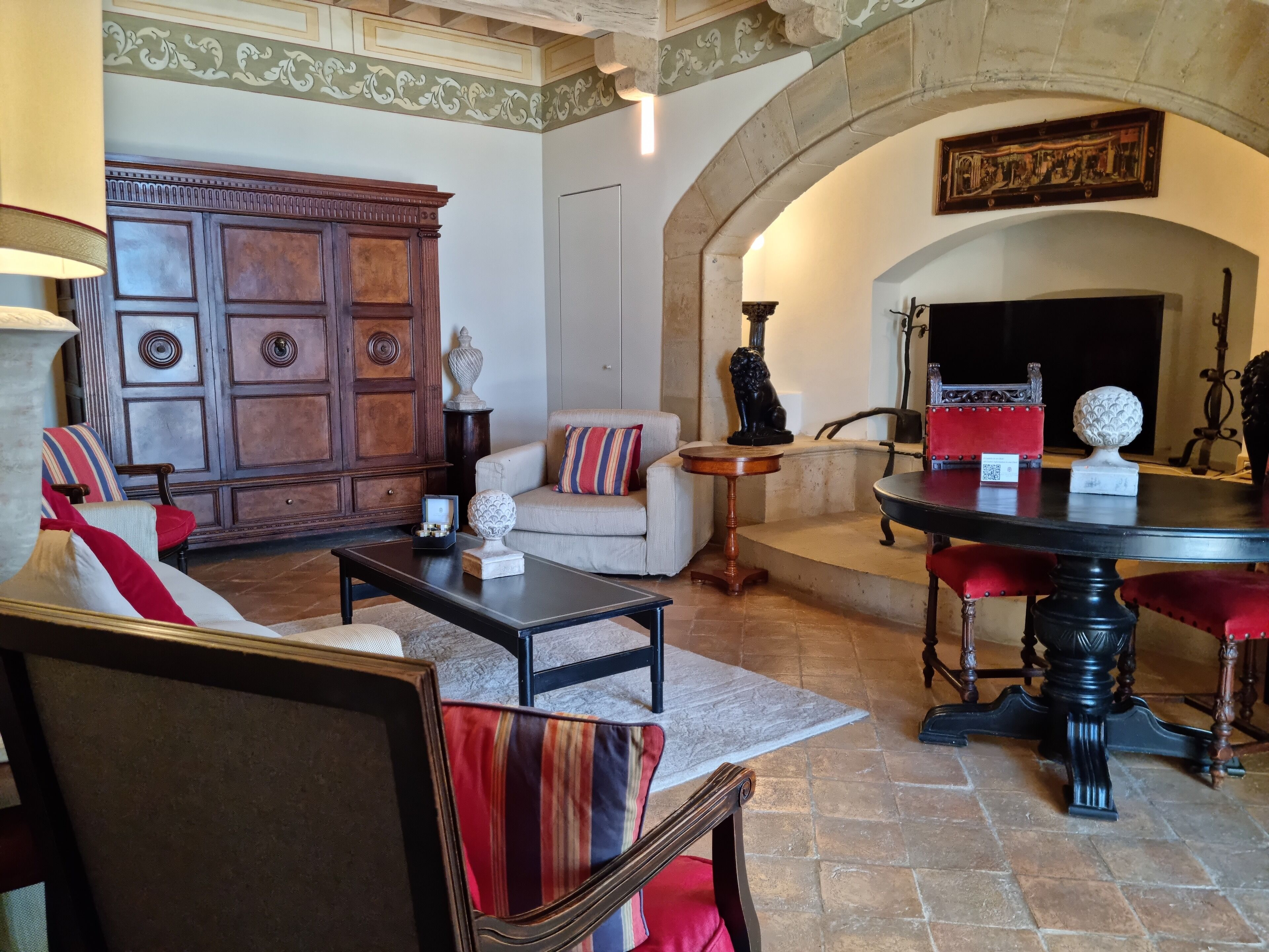 A spacious living room with a fireplace, a wooden cabinet, a sofa, and a dining table.