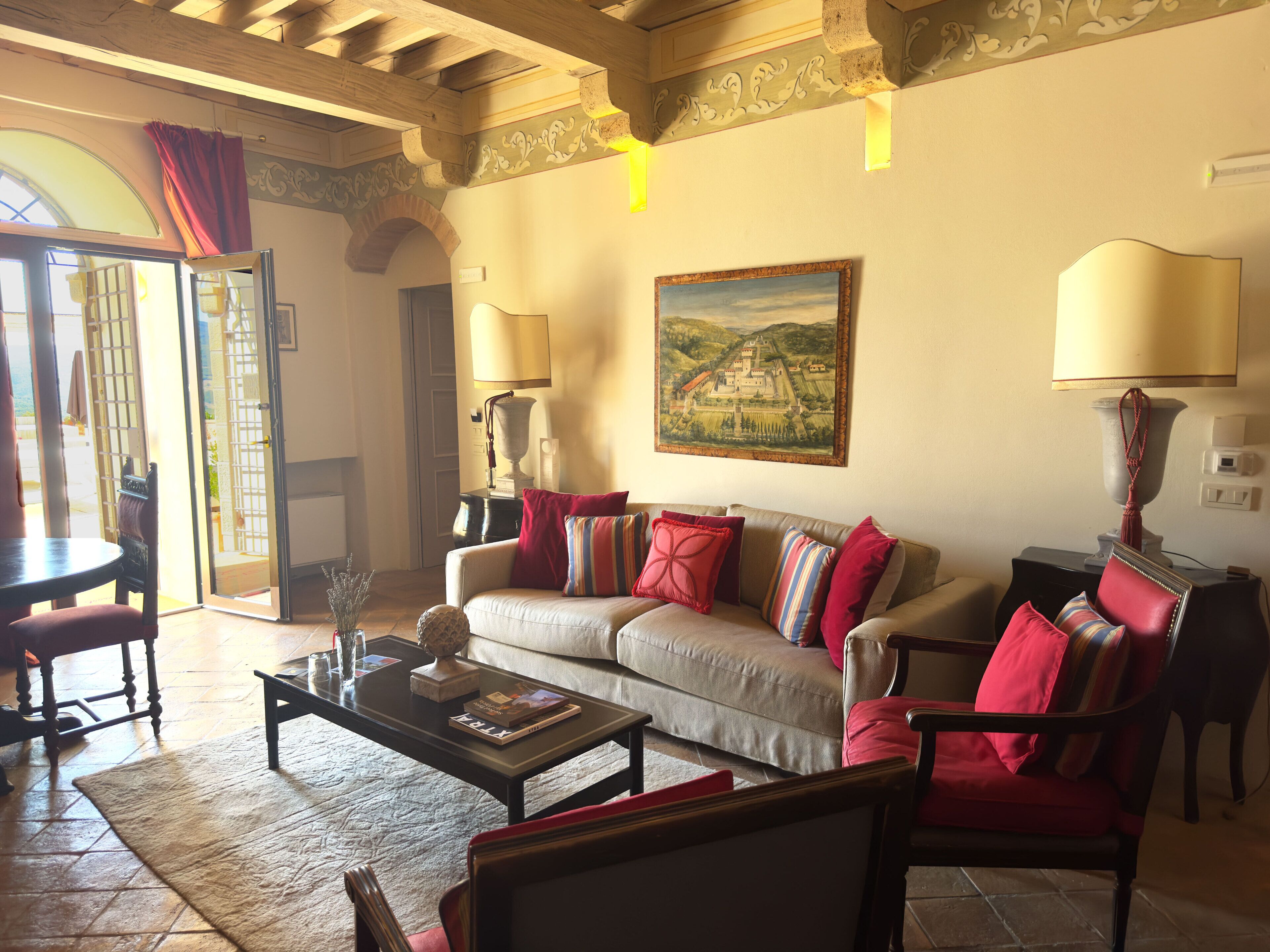 A living room with a sofa, armchairs, a coffee table, and a painting on the wall.