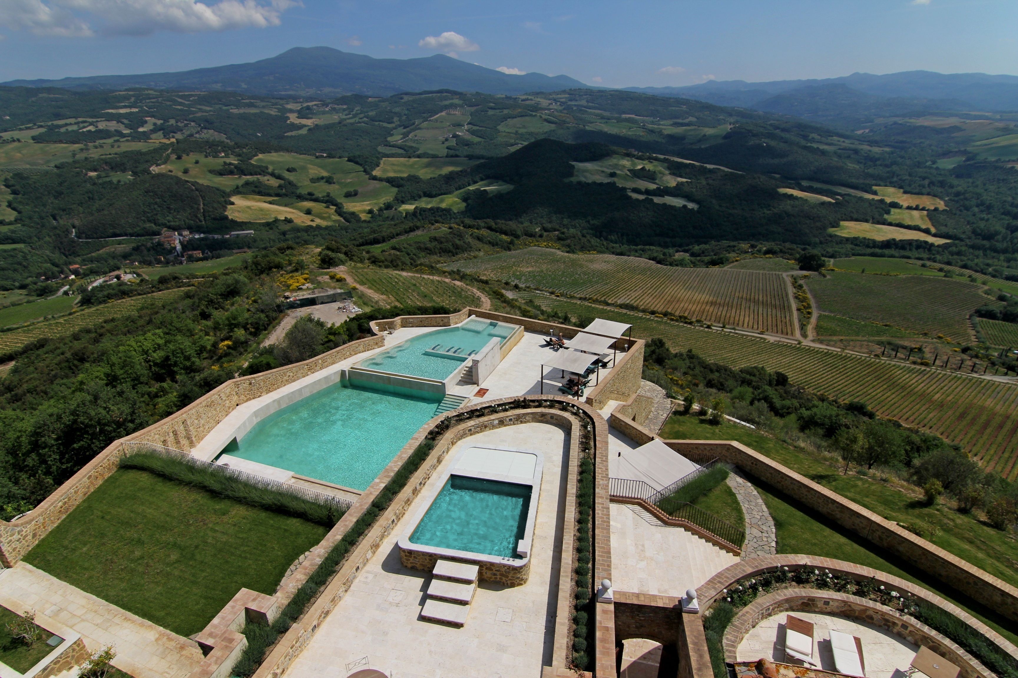 Una amplia piscina rectangular rodeada de muros de piedra, con una piscina más pequeña contigua.