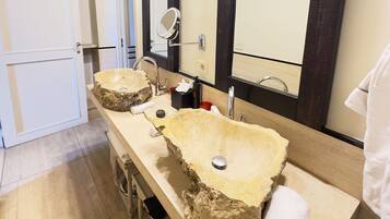 Un baño con dos lavamanos de piedra grandes, un espejo y un perchero para toallas.