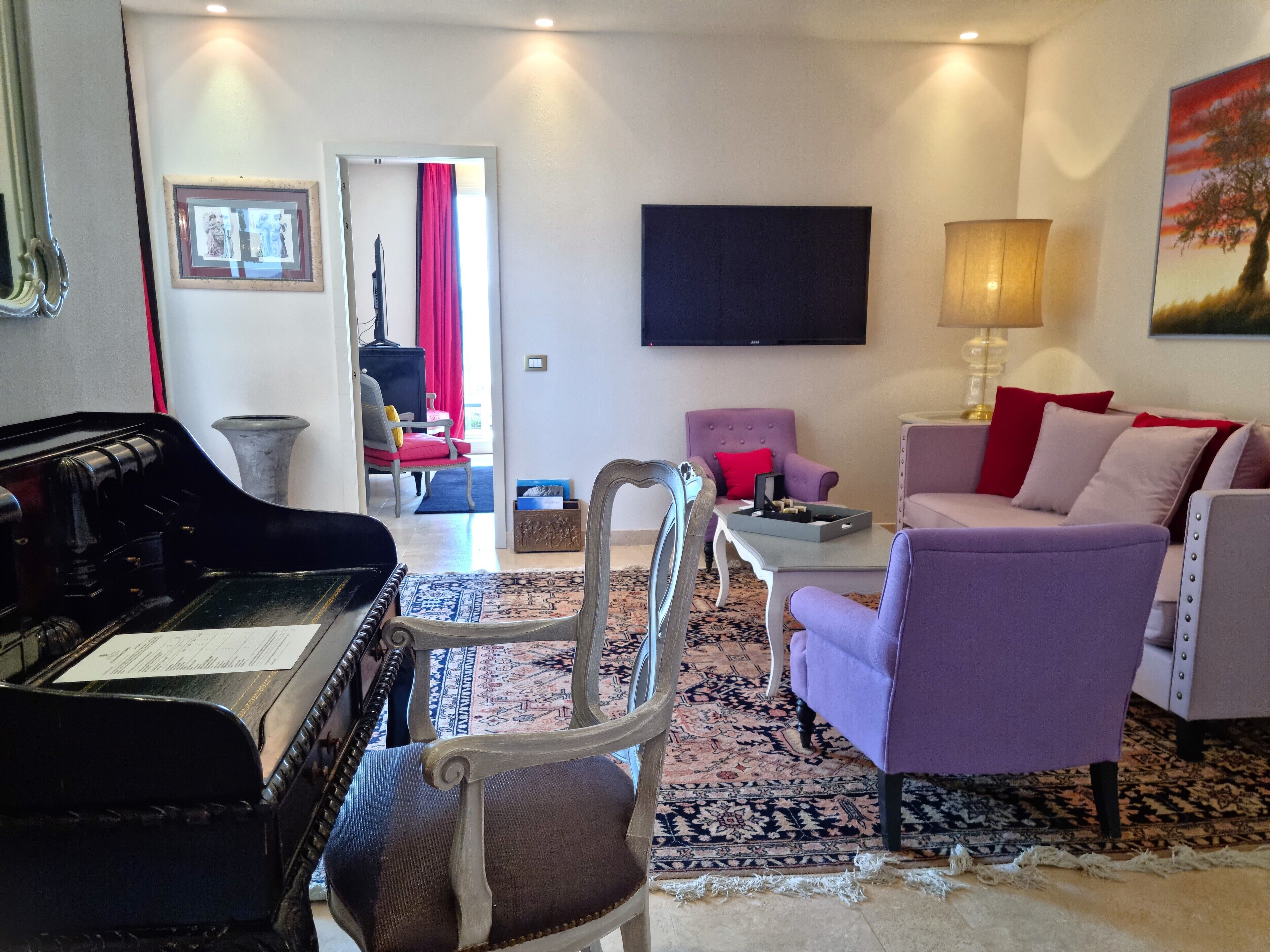 Een woonkamer met een vleugelpiano, een televisie en een bank.