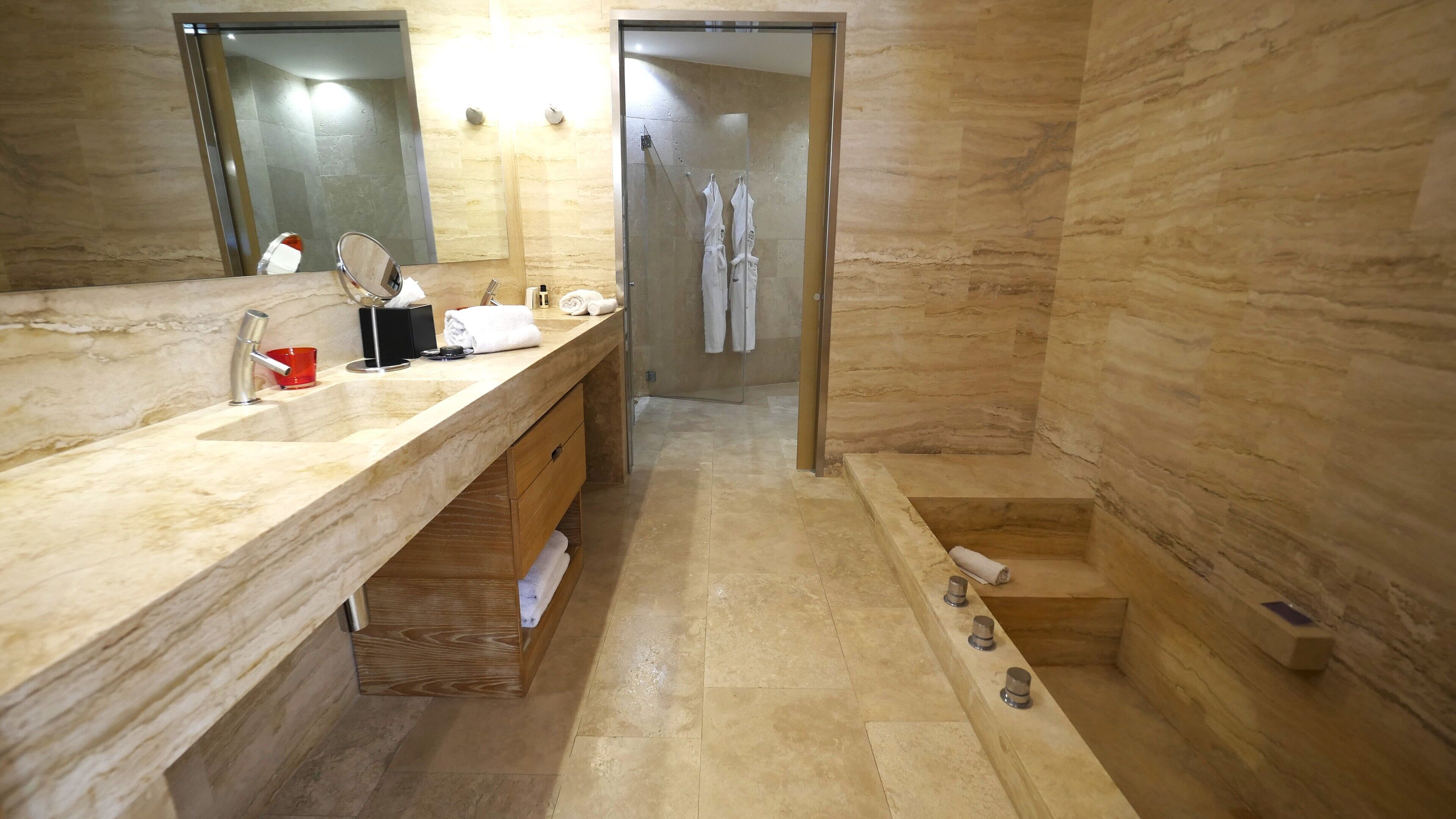 A modern bathroom with a marble sink, a glass shower enclosure, and a wooden vanity.