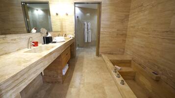 Un bagno moderno con lavabo in marmo, cabina doccia in vetro e mobile vanitario in legno.