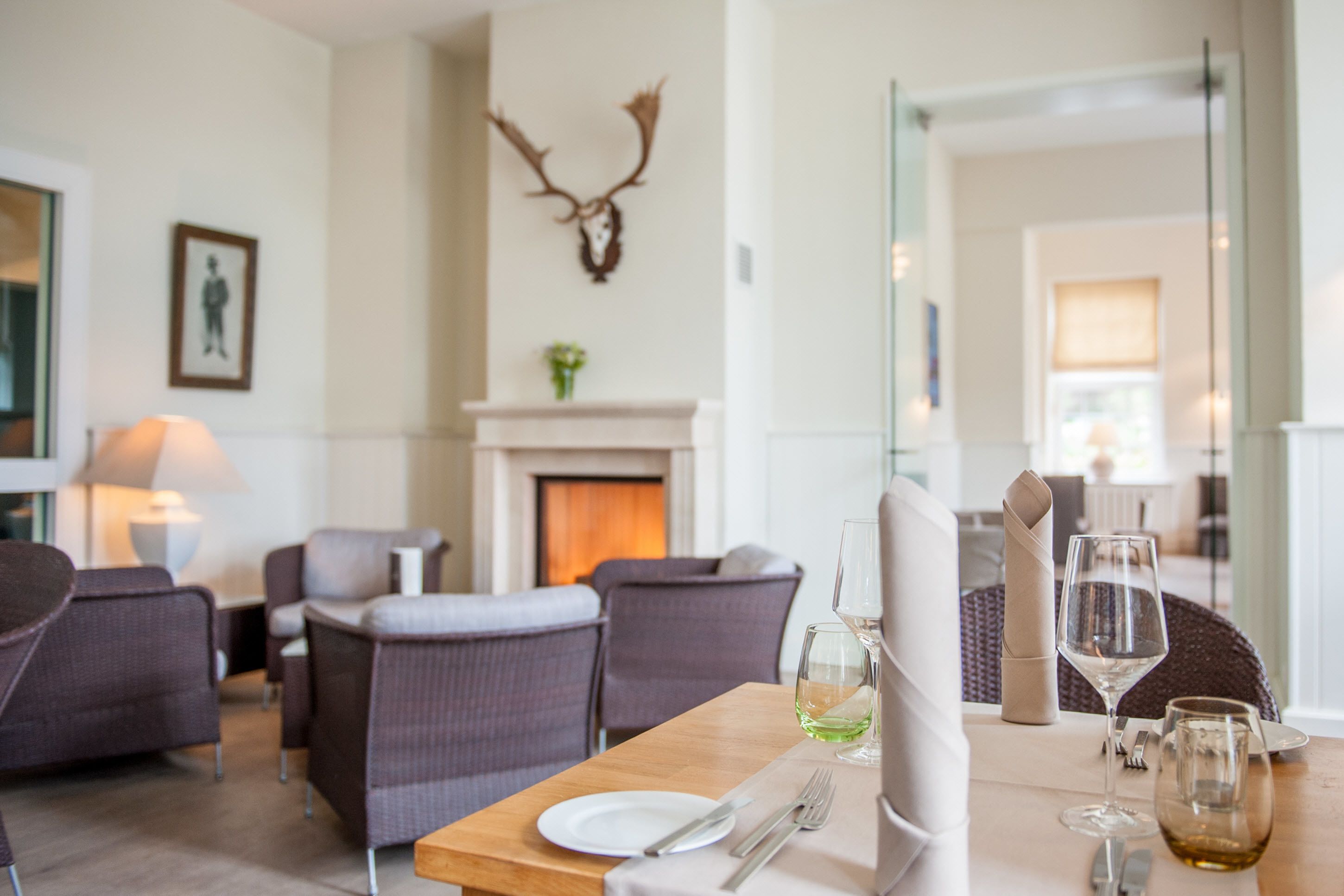 Un comedor con una mesa de madera preparada para dos, una chimenea y muebles modernos.
