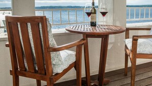 A wooden deck with a table and chairs, overlooking a body of water.