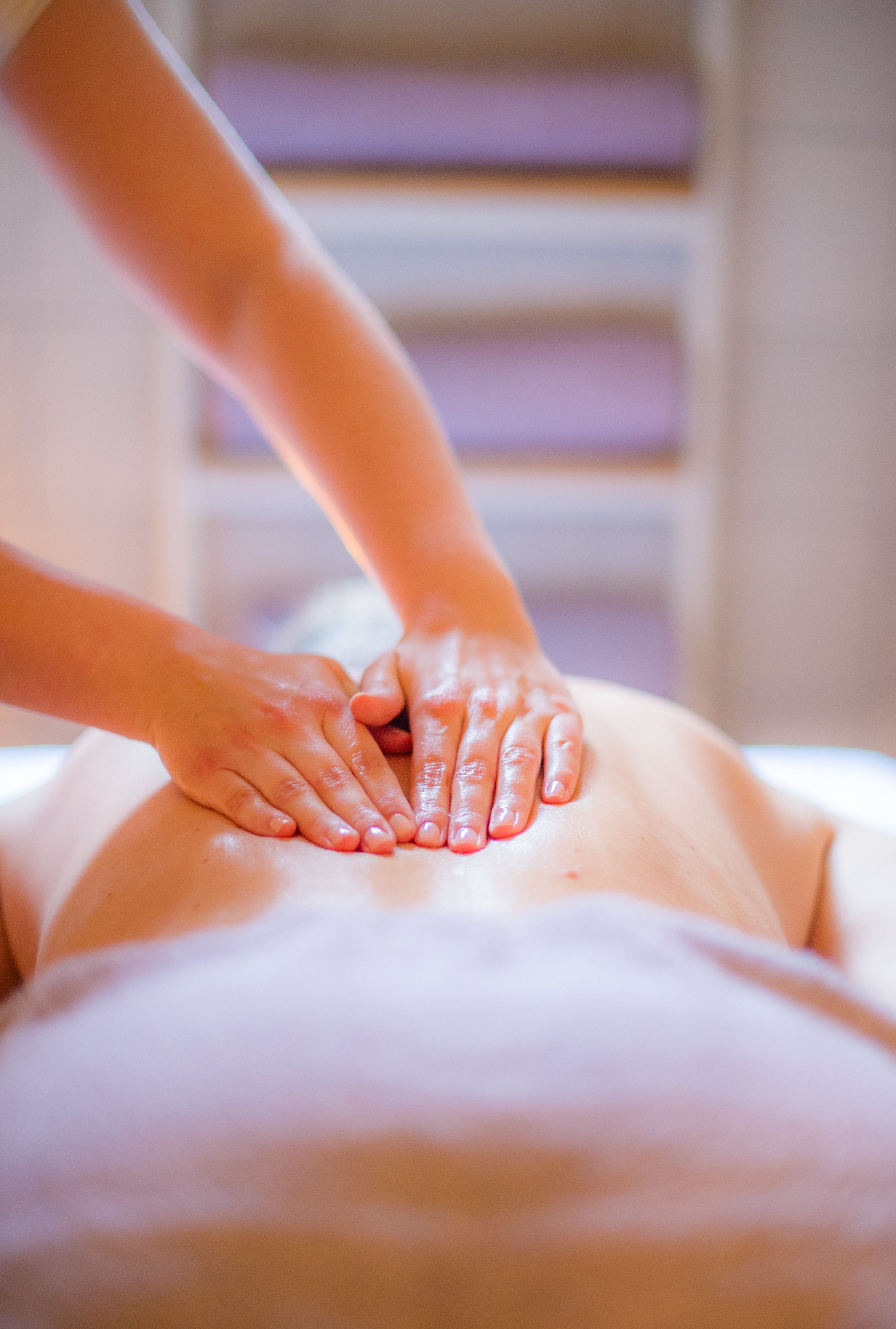 A massage therapy session with hands on a person's back.