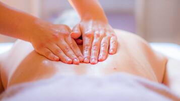 A massage therapy session with hands on a person's back.