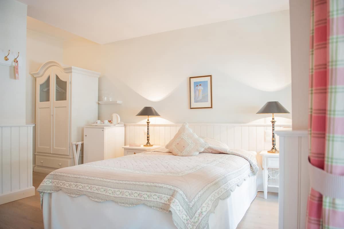 A bedroom with a bed, two bedside tables, a wardrobe, and a framed picture on the wall.