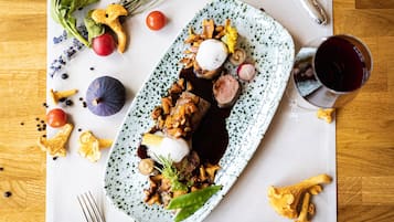 Un plato de comida con diversos vegetales y una copa de vino tinto.