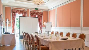 A conference room with a long table, chairs, a whiteboard, and a chandelier.