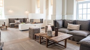 A spacious living room with a large sectional sofa, a white coffee table, and a fireplace.
