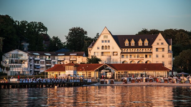 A large, historic building with multiple stories and a prominent entrance, located near a waterfront.