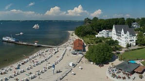 A coastal hotel with a beach, a pier, and a large building.