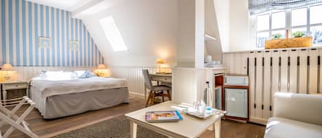 A bedroom with a bed, desk, chair, and a small refrigerator.