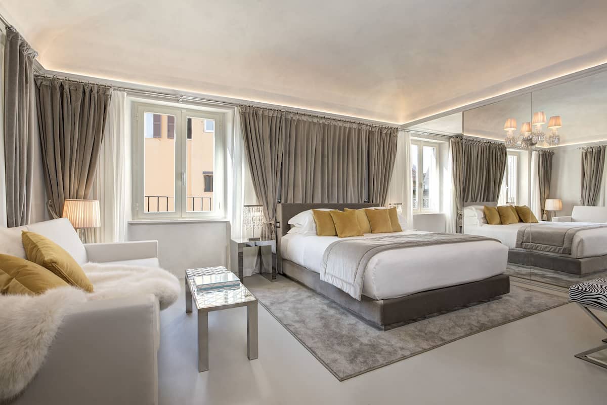 Une chambre d’hôtel moderne avec un grand lit, un canapé, une petite table et un miroir.