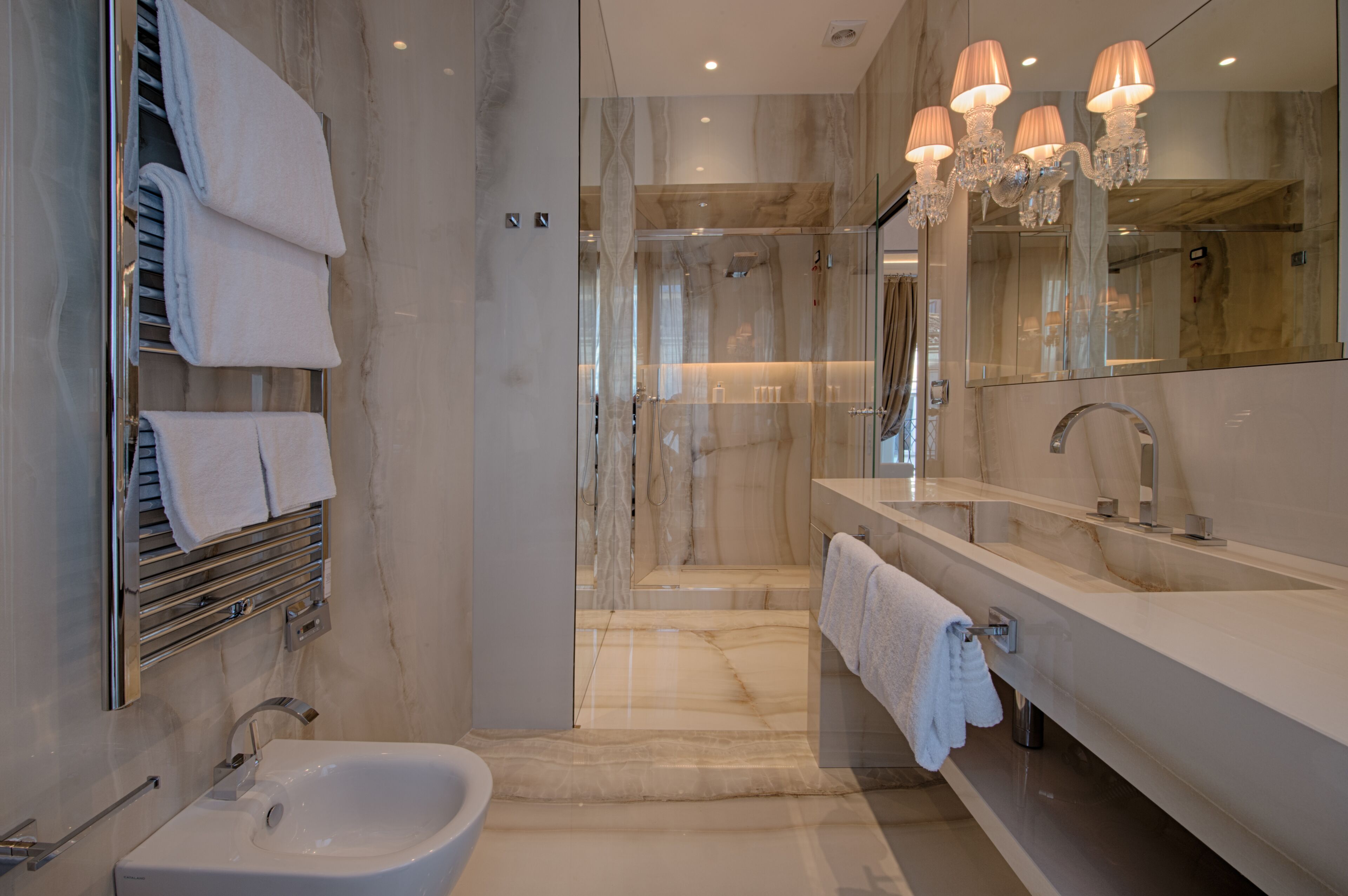 A modern bathroom with a large mirror, a sink, a bidet, and a shower area.