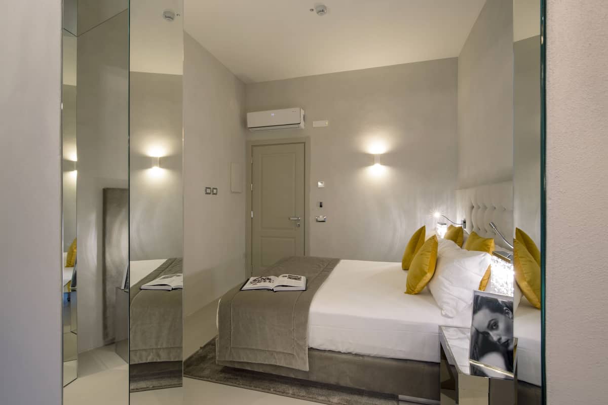 Une chambre d’hôtel moderne, équipée d’un lit, d’une table de chevet et d’un miroir.
