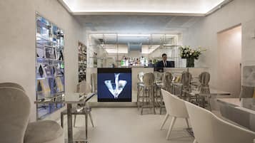 A modern bar area with a bartender, glass display shelves, and a large screen.