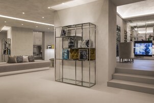 A modern interior with a glass display case, a sofa with cushions, and a television in the background.