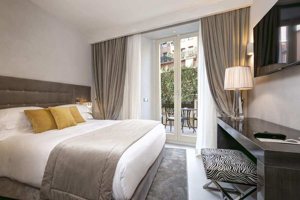 Une chambre d’hôtel avec un grand lit, un bureau, une chaise et une vue sur le balcon extérieur.