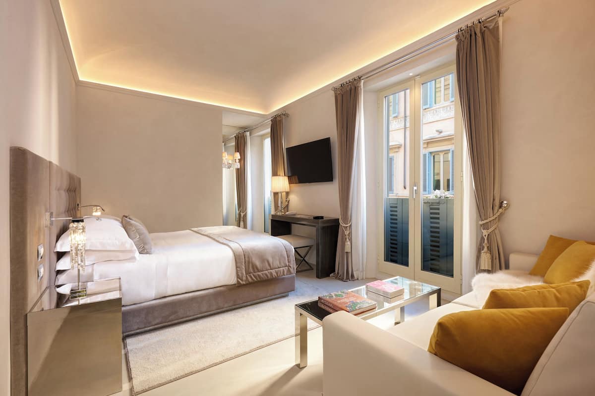 Une chambre d’hôtel avec un lit, un bureau, une télévision et un canapé.