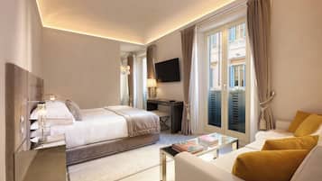 Quarto de hotel com uma cama, uma escrivaninha, uma televisão e um sofá.