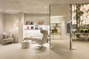 A modern interior with a white sofa, a unique chair, a marble coffee table, and a glass partition with framed pictures.