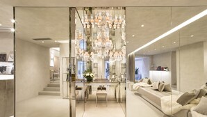Un interior de hotel moderno con una escalera central, un área de descanso con una manta de piel y un candelabro.