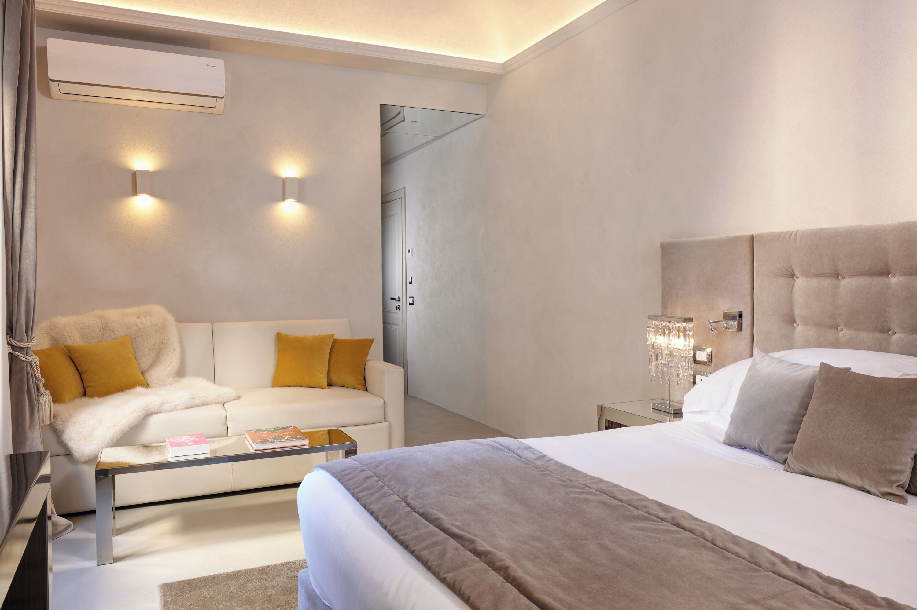 Una habitación de hotel moderna con una cama, un sofá, una mesa de centro y un aire acondicionado instalado en la pared.