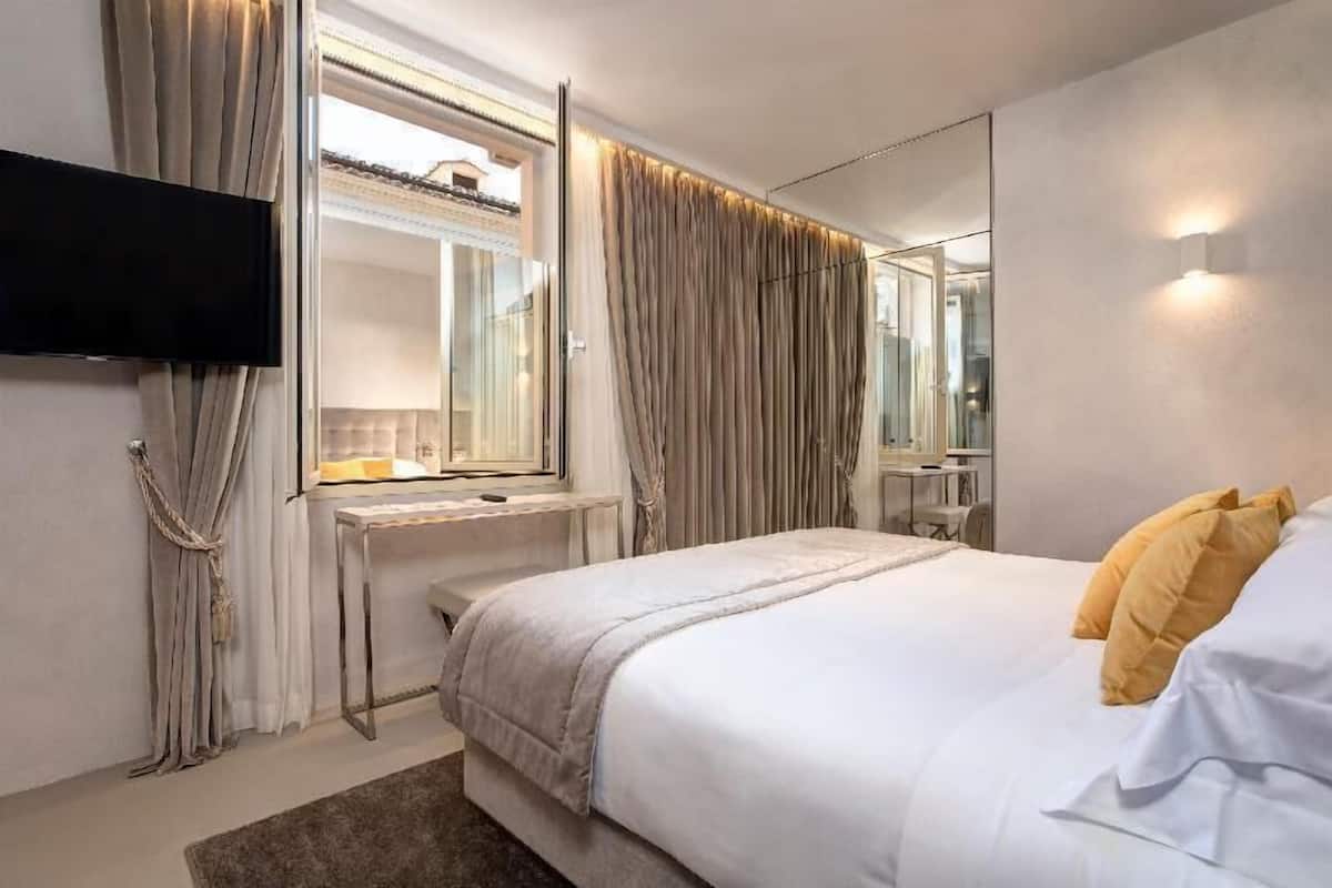 Une chambre moderne avec un lit, une télévision, une fenêtre avec des rideaux et un miroir.