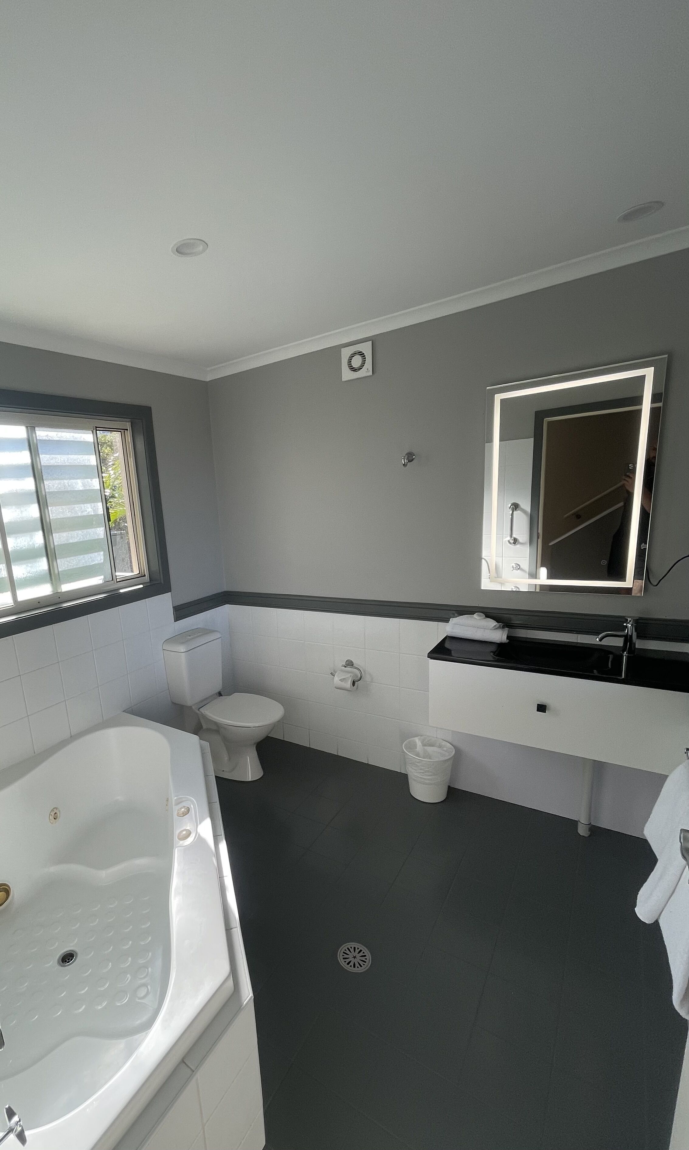 A modern bathroom with a bathtub, toilet, and vanity.