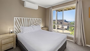 A hotel room with a large bed, a nightstand, a bedside lamp, and a window with curtains. - Aqualuna Beach Resort (Korora)