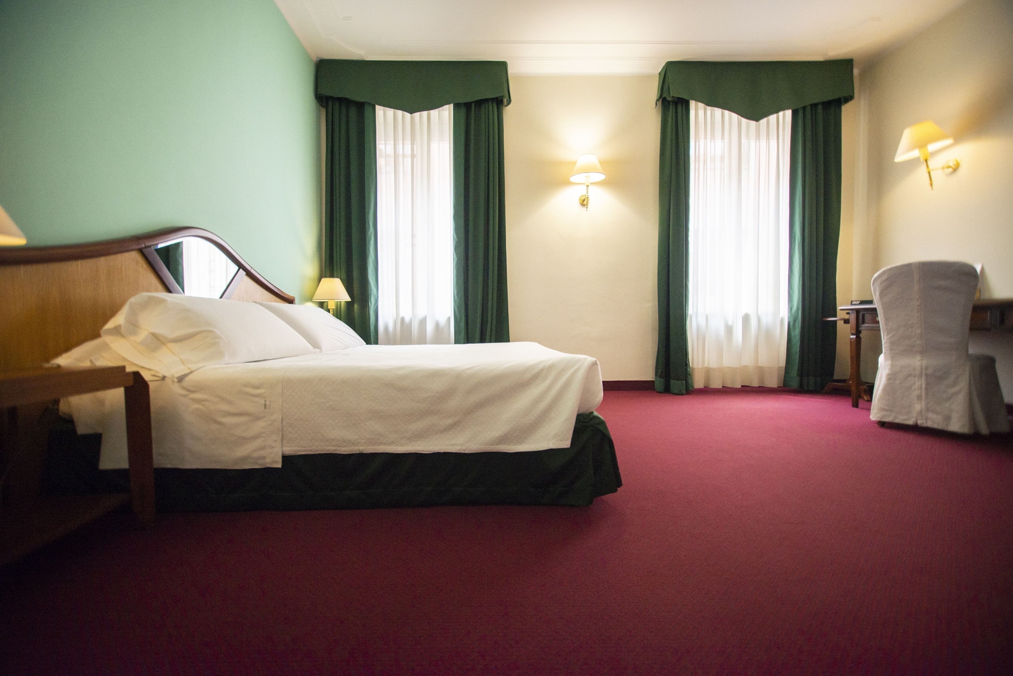 Una habitación de hotel con una cama, un escritorio y dos lámparas.