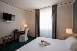 A hotel room with a bed, a desk with a chair, a television, and a breakfast tray on the bed. - Hotel Alli Due Buoi Rossi (Alessandria)