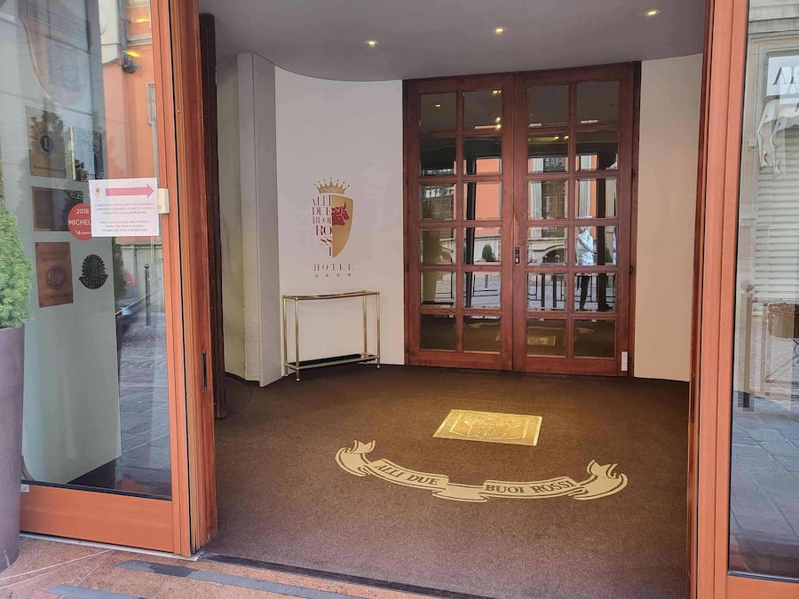 En hotelindgang med en glasdør, et skilt der viser en Michelino-pris fra 2018, og en logo på væggen.
