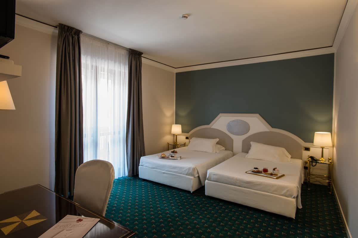 Een hotelkamer met twee bedden, een bureau en een stoel.