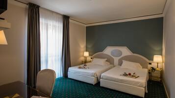 Une chambre d’hôtel avec deux lits, un bureau et une chaise.