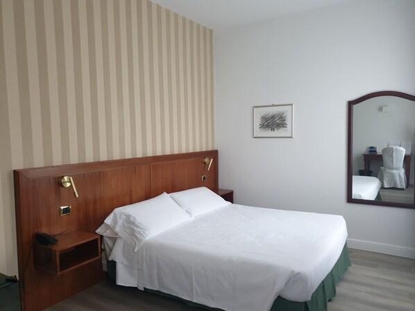 A neatly made bed with white linens, a wooden headboard, a bedside table with a telephone, and a framed picture on the wall. - Hotel Alli Due Buoi Rossi (Alessandria)