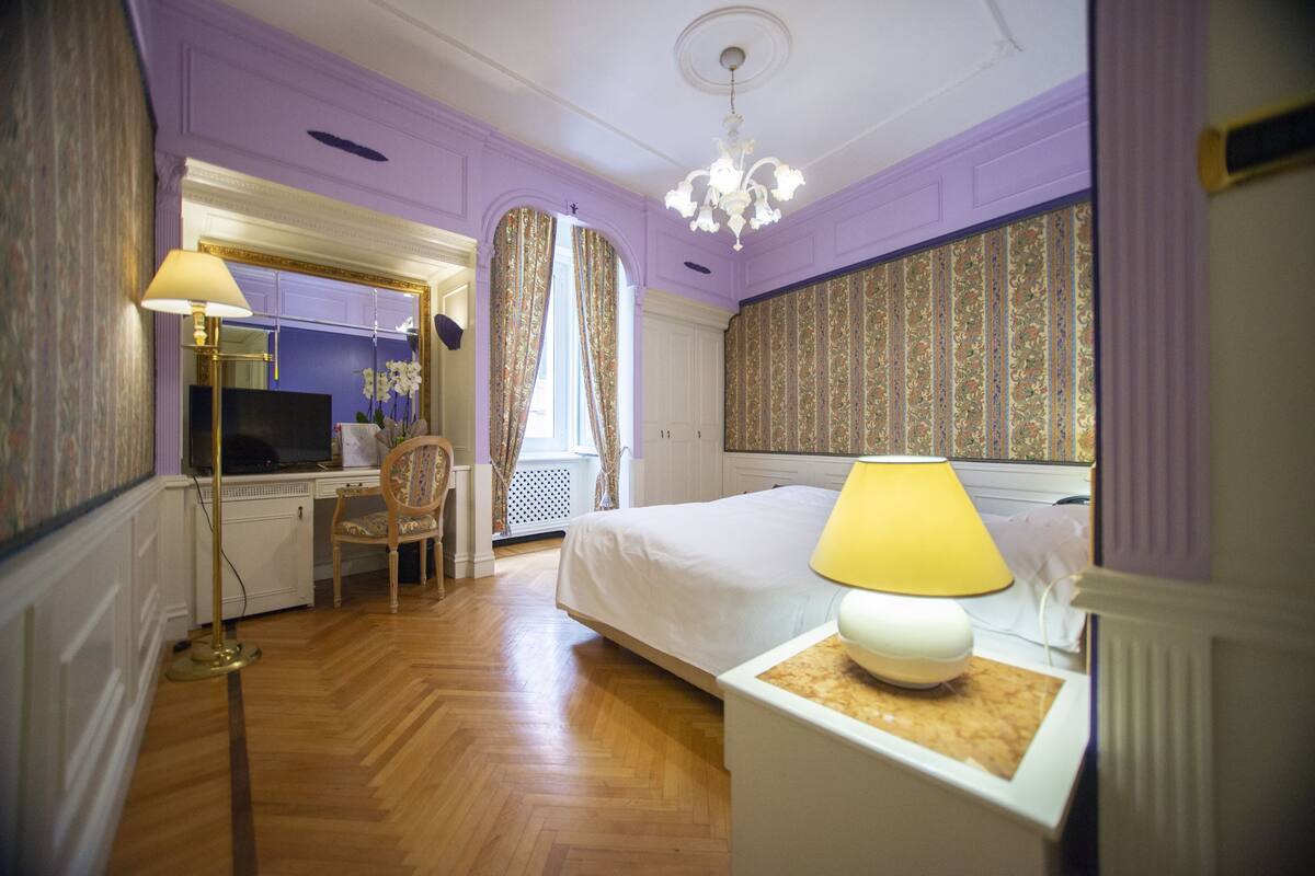Een hotelkamer met een bed, bureau met computer, stoel en televisie.