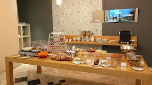 Een ontbijtbuffet met diverse gerechten, een koffieapparaat en een zithoek met uitzicht op het omliggende landschap.