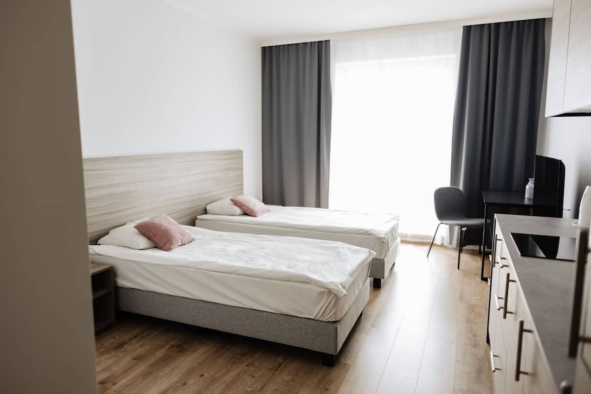 Quarto de hotel com duas camas, uma escrivaninha e uma cadeira.