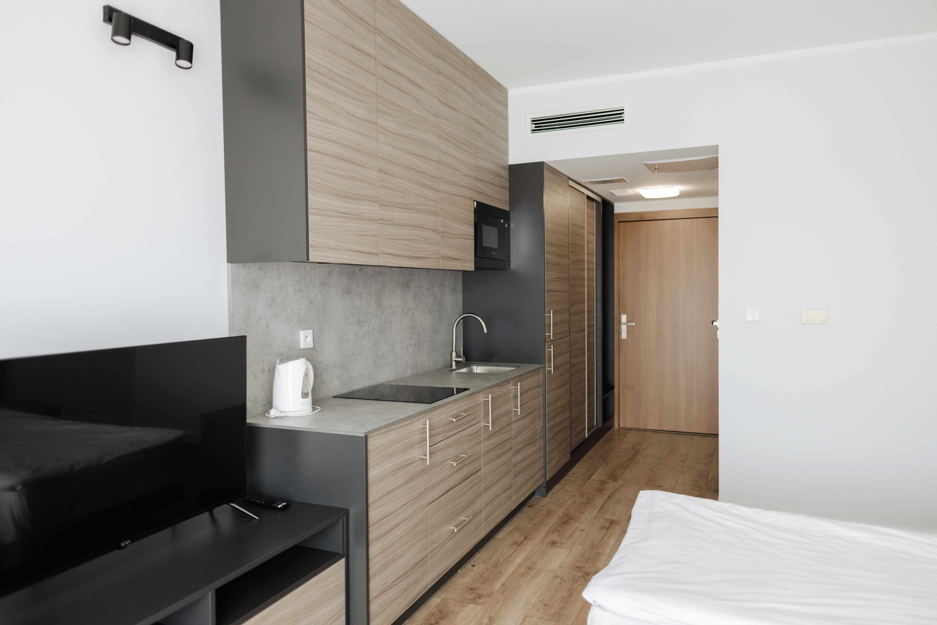 A modern kitchenette with a built-in microwave, a sink, and a coffee maker.