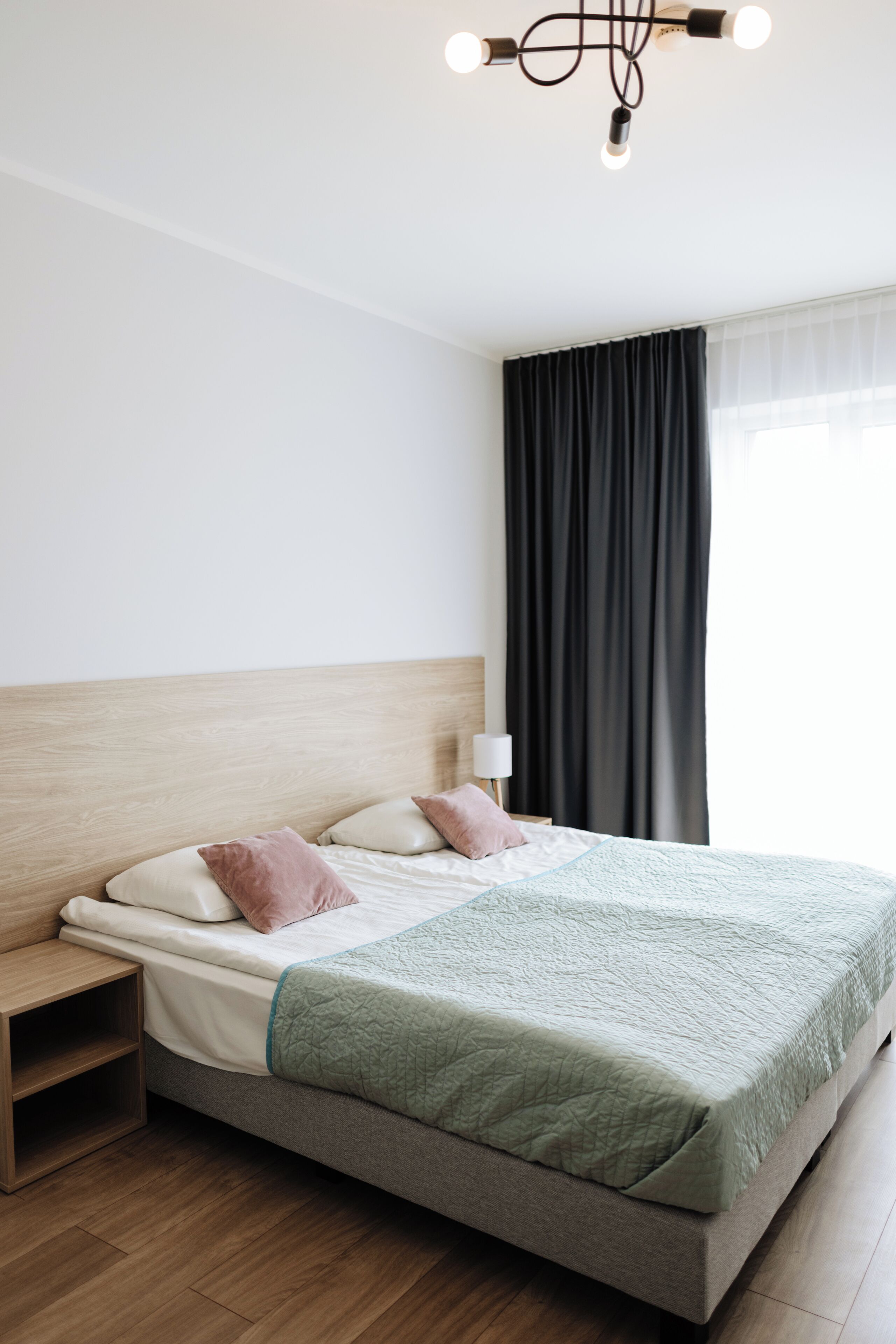 A neatly arranged hotel room with a bed, bedside table, and a lamp.