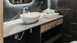 A modern bathroom with a marble sink, a large mirror, and neatly folded towels.