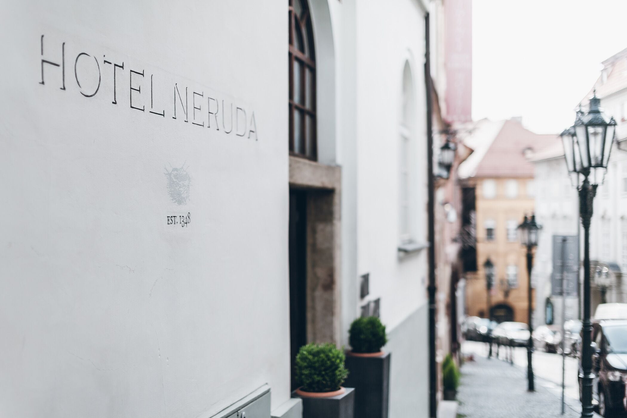 A narrow street with a building labeled "HOTEL NEURUDA" and a cobblestone path.