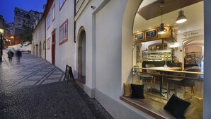 Eine Kopfsteinpflasterstraße mit einem Café, das eine Glastheke und einen Sitzbereich zeigt.