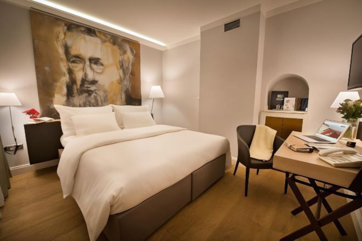 Une chambre d’hôtel avec un grand lit, un bureau avec une chaise, une télévision et un tableau au mur.